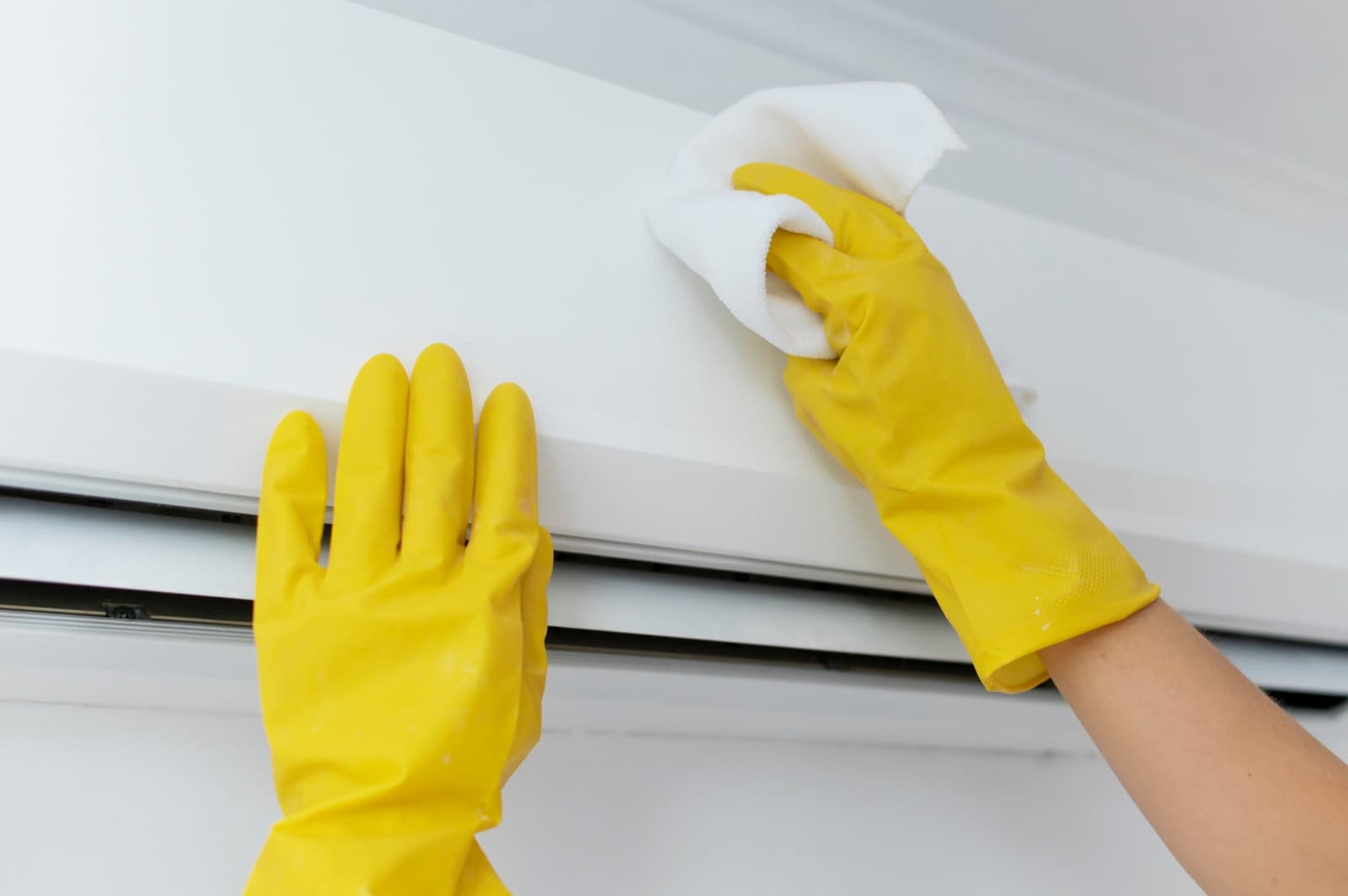 Gloved hands deep-cleaning a wall-mounted split AC